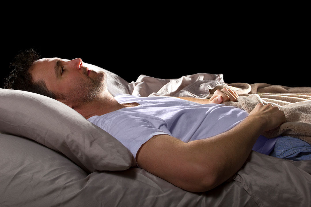 Man with insomnia lays awake in his bed in the middle of the night
