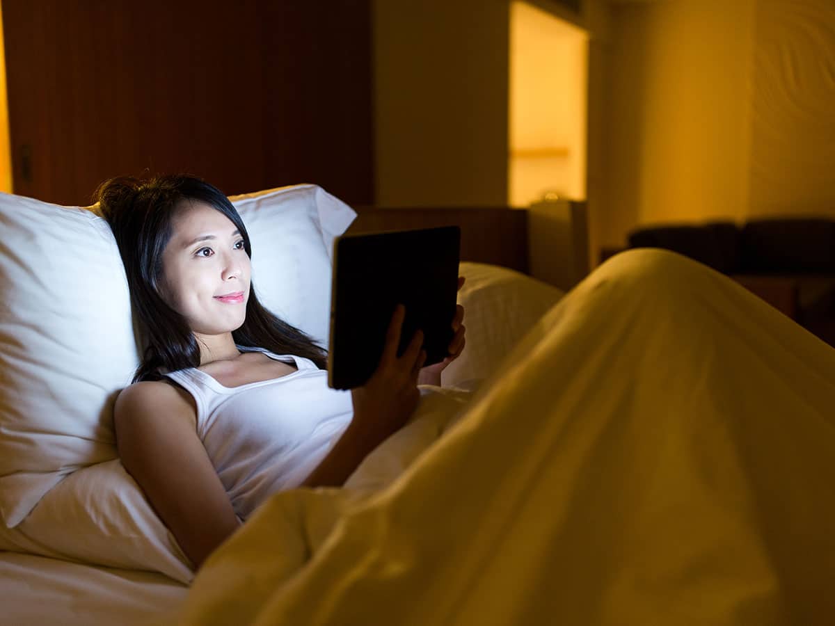 Woman risks sleep deprivation staying up late watching tv in bed