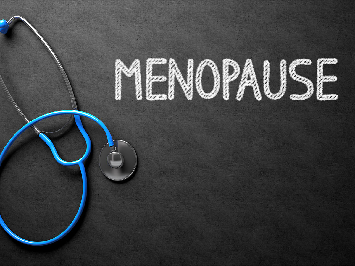 Word Menopause written on a chalkboard next to a stethoscope