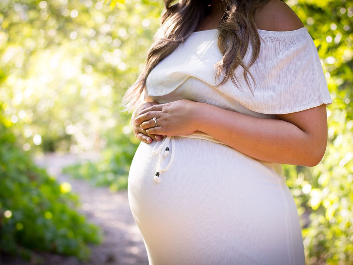 pregnant woman standing near green plants