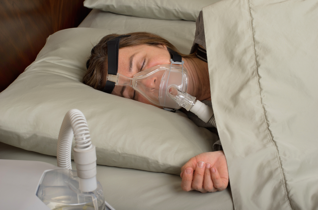 Middle-aged woman with sleep apnea uses CPAP machine