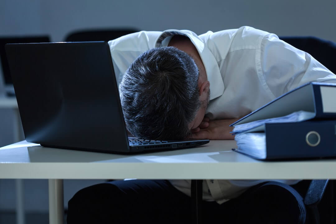 man stressed at work has his head on his office desk