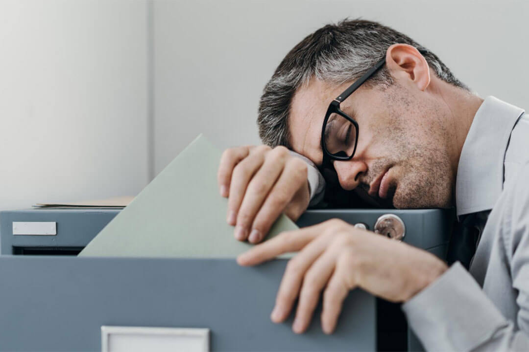Man With Narcolepsy Falls Asleep On A Filing Cabinet At Work