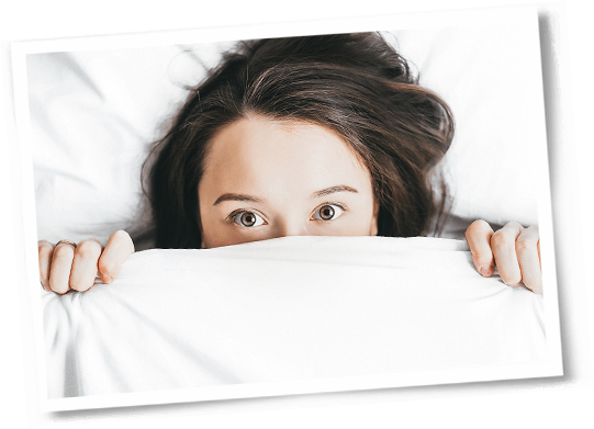 woman only showing eyes under sheets in bed