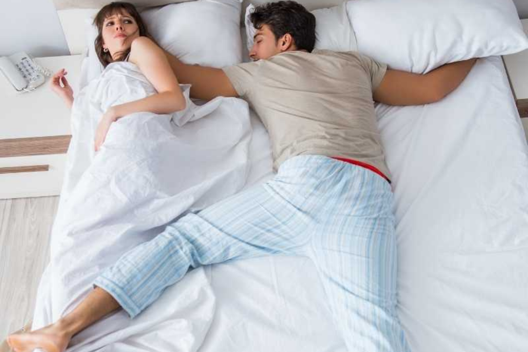sleeping man sprawled over partners side of bed