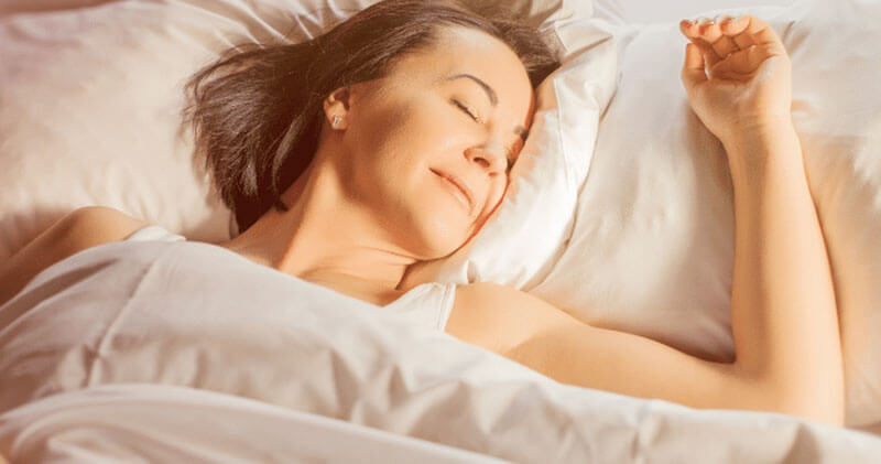 Woman Happily Sleeping in Bed with Morning Sun Shining wide