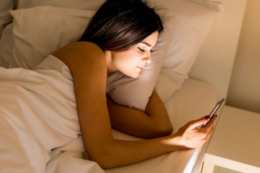 Woman looking at her phone in bed