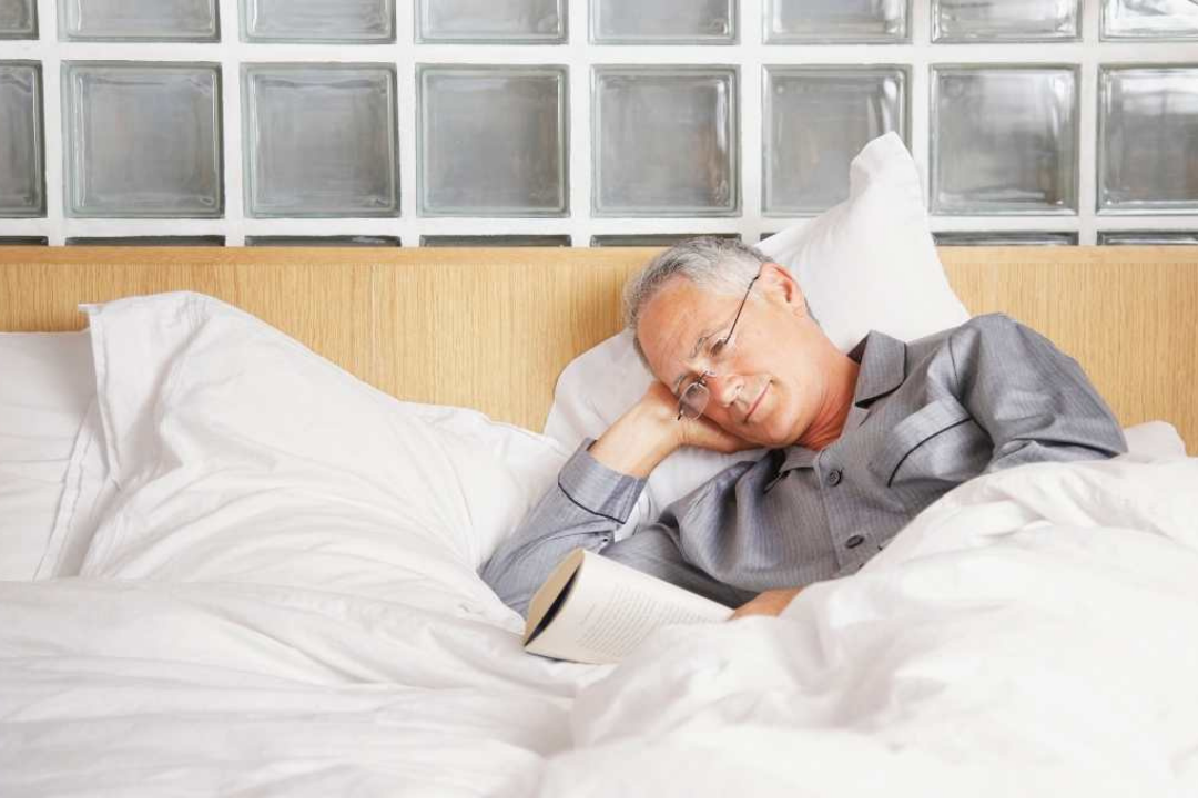 Man reading a book in bed.