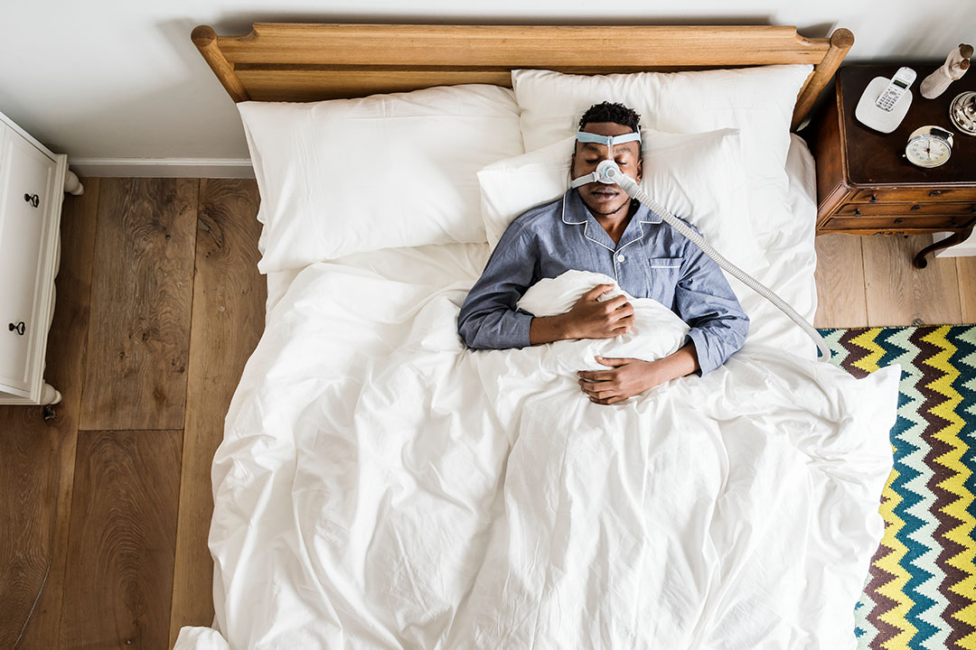 Young man sleeping in bed wearing a cpap mask