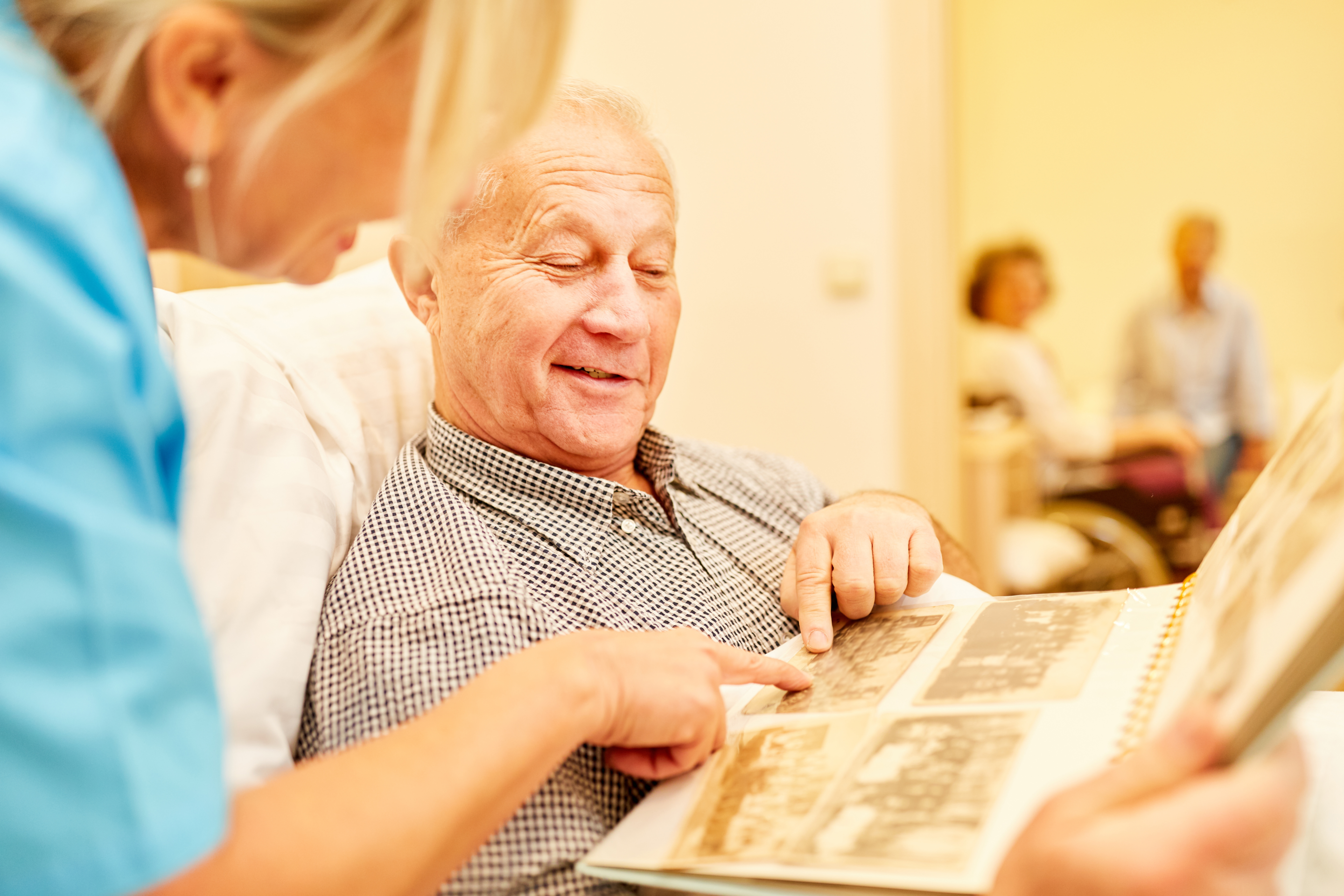 Senior man with Alzheimer's disease looks at photo album in bed.