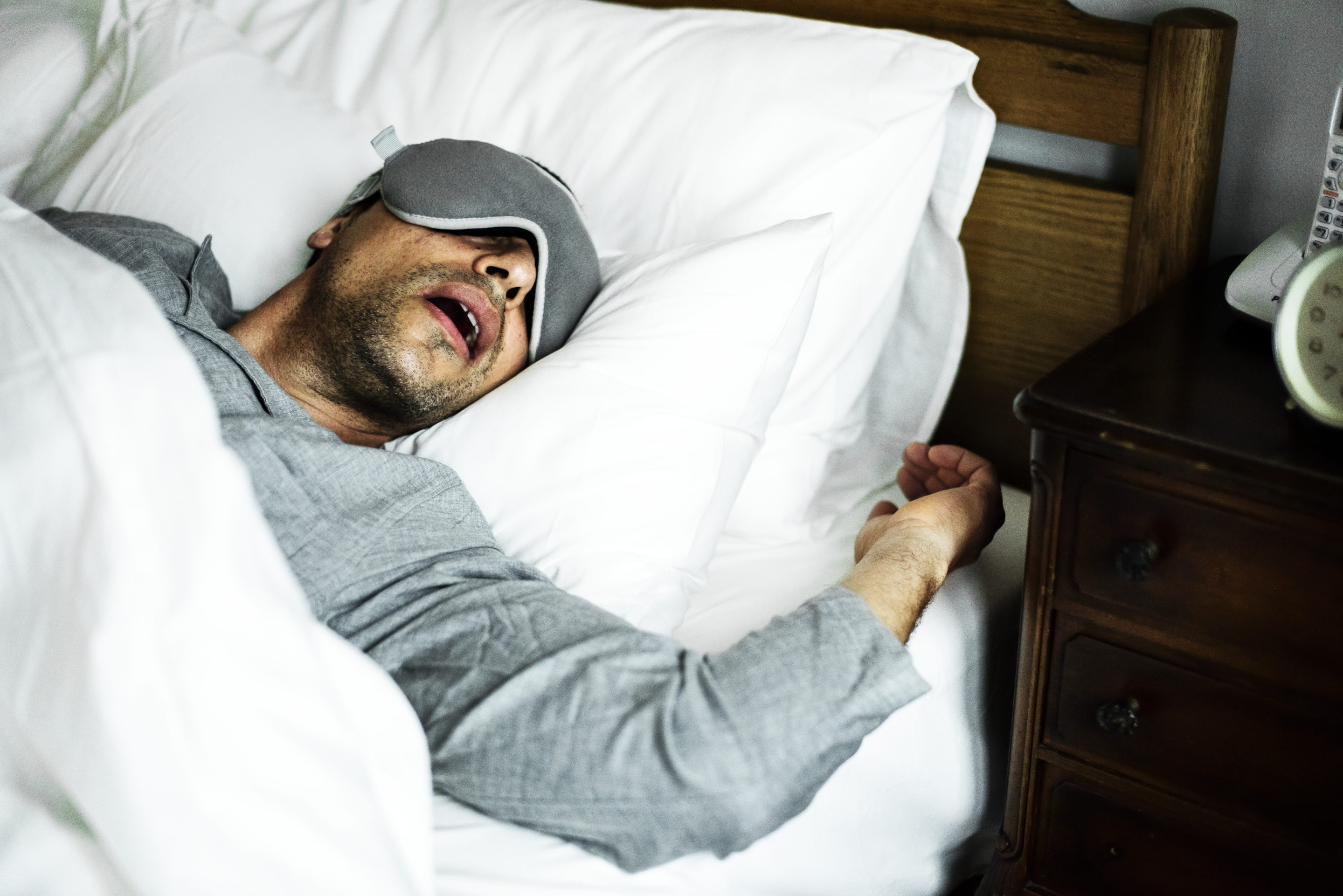 A man with sleep apnea snoring loudly while asleep in bed.