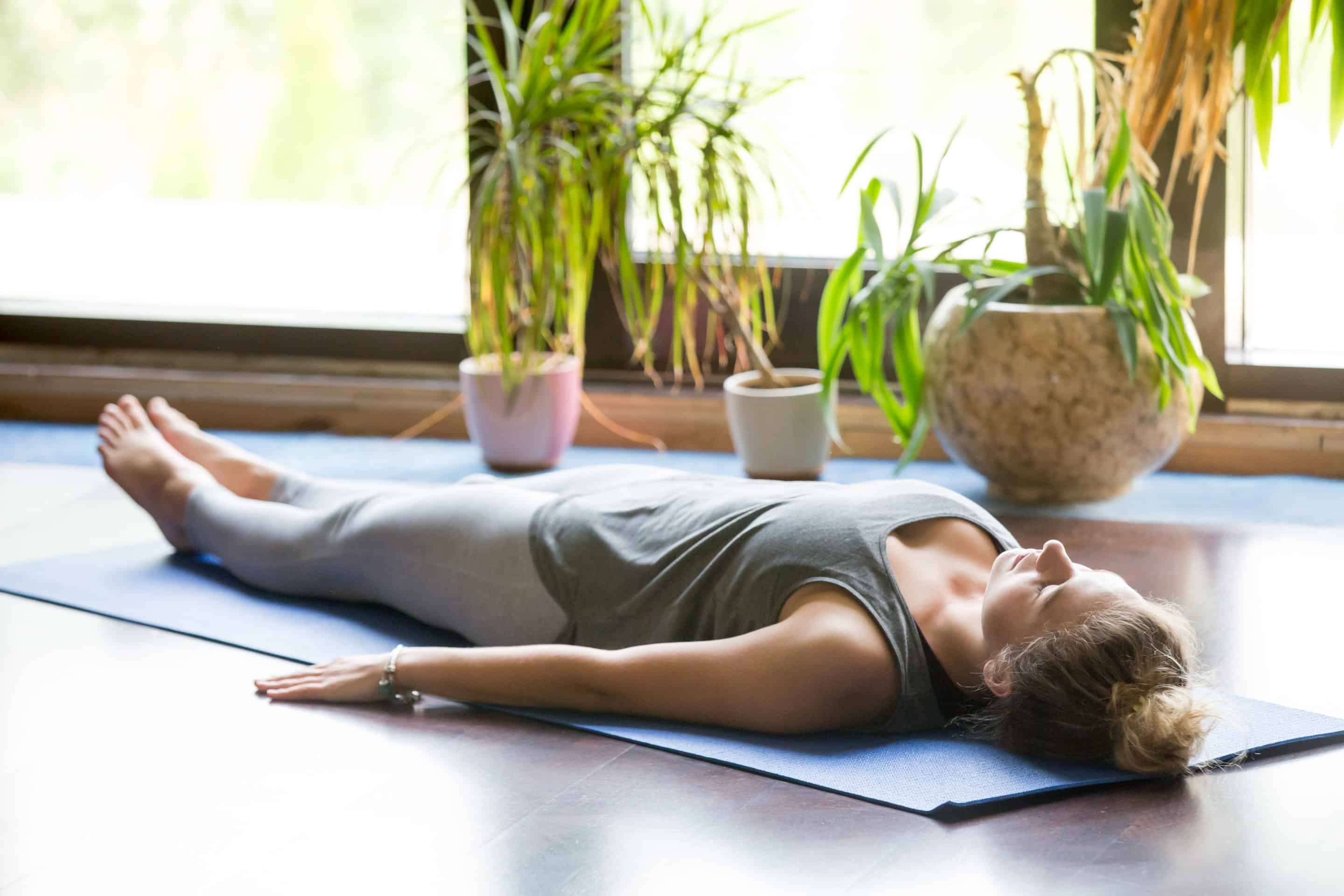 A woman practicing yoga nidra on a yoga mat