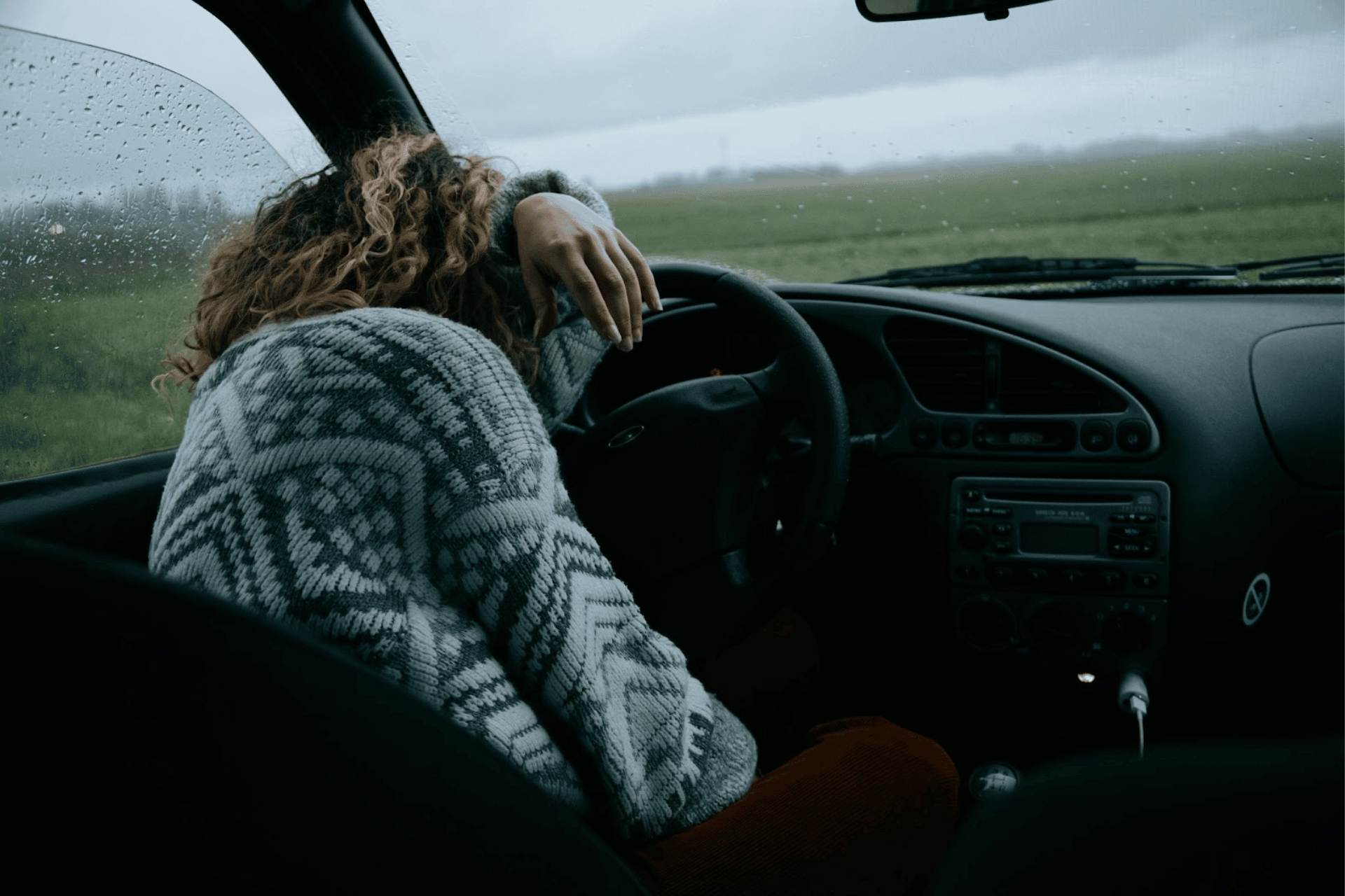 A tired driver rests their head on the steering wheel.