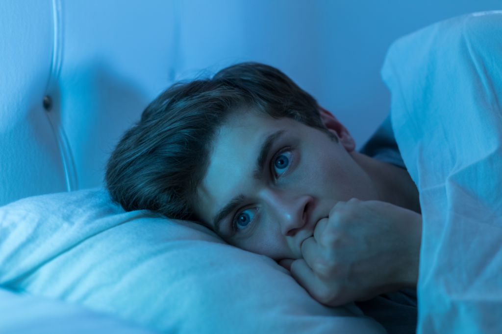 A nervous man laying awake in bed.