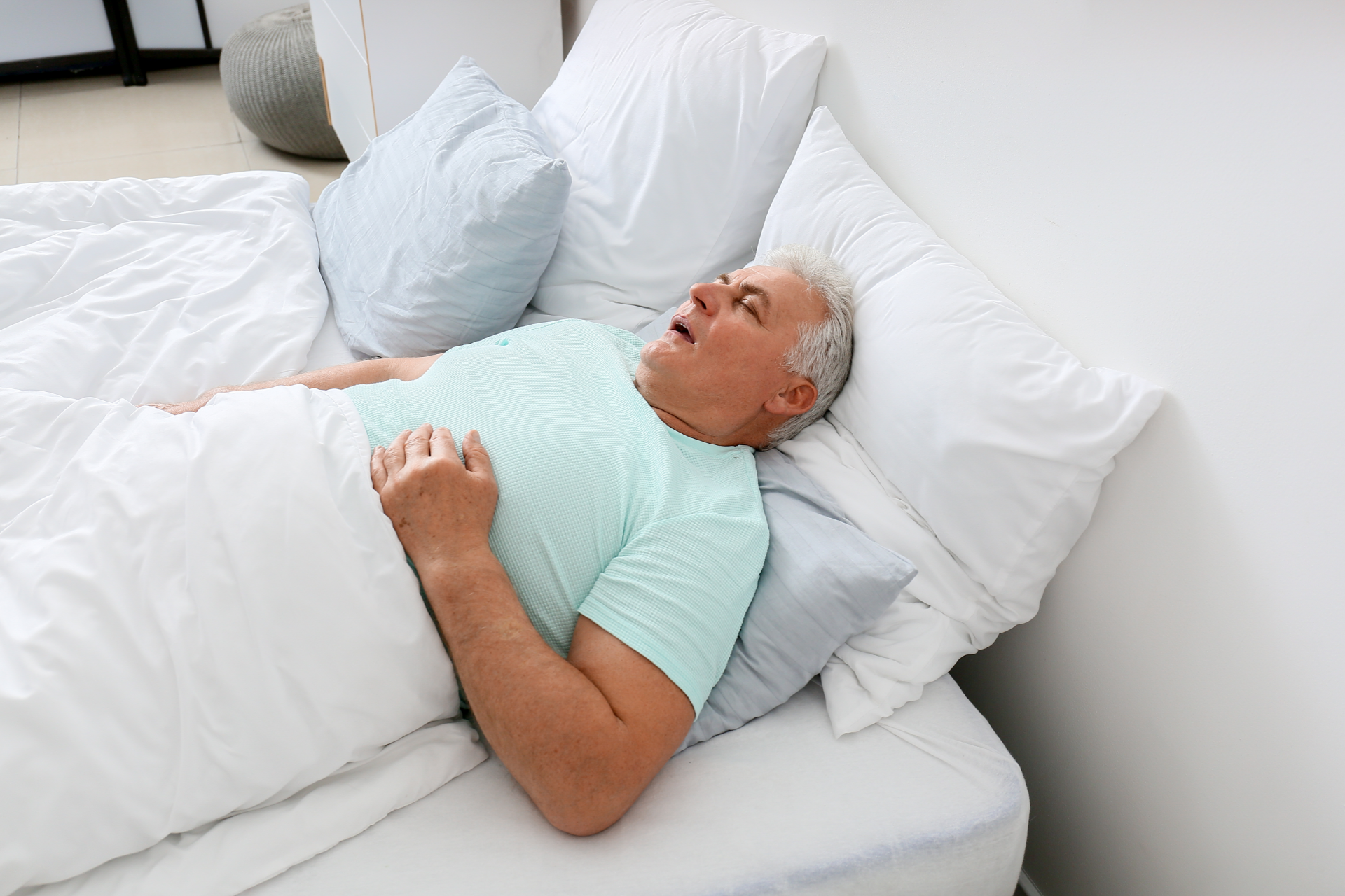 A senior man snoring in bed.