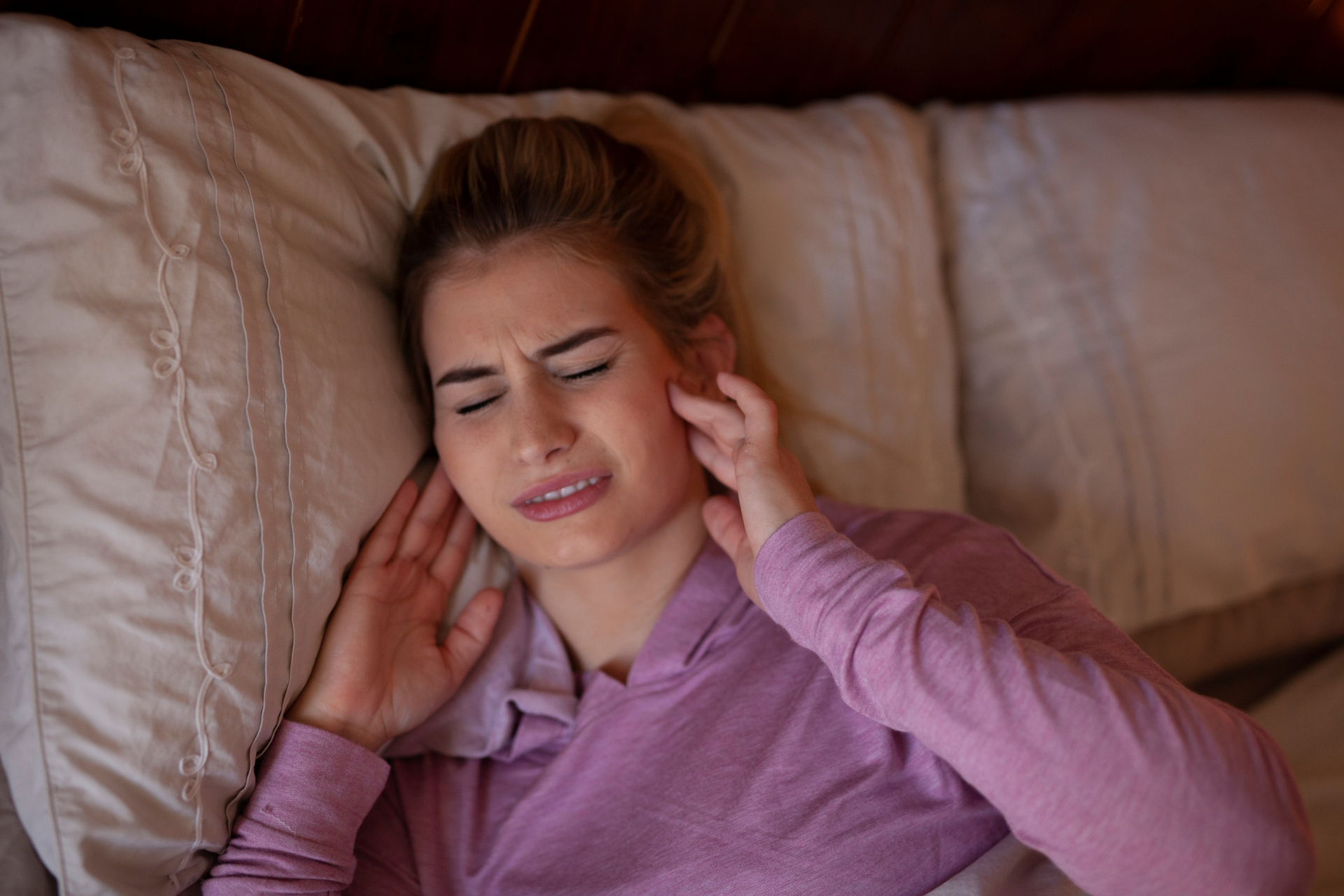 A woman with jaw pain laying in bed.